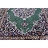 An Eastern style carpet with central medallion on a green ground within a figured floral border,