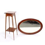 An early 20th Century oval wall mirror, 95cm wide and a mahogany two-tier jardinière stand,