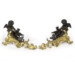 A pair of Louis XV bronze and ormolu chenets, each modelled as a cherub wrestling a chimera,