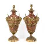 A pair of red mottled marble vase shaped reading lamps with gilt metal ram masks and floral swags,