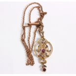 An Edwardian 9ct gold pendant, the openwork frame set seed pearls and pink gems to a 9ct gold chain,