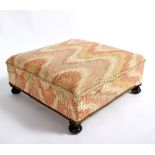 A square upholstered stool with brass rope border,