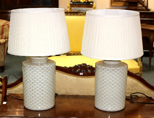 A pair of modern ceramic table lamps, each with geometric decoration to a cream ground,