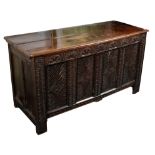 A 17th Century oak chest, the hinged cover above a carved front, on block feet,
