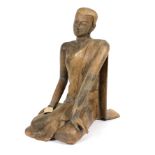 An 18th century Siamese carved wood Buddha, seated with legs to the right hand side,