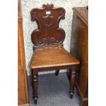 Two early Victorian mahogany hall chairs with cartouche shaped backs on turned front legs