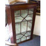 An early 19th Century mahogany corner cupboard, enclosed by a glazed border,