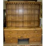 An elm dresser with associated oak shelves over, the base fitted seven drawers with recess beneath,
