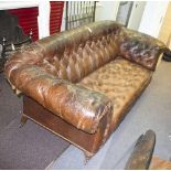 A late 19th Century upholstered sofa with leather buttoned upholstery, on turned front legs,
