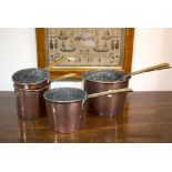 A group of five copper pans with brass handles,