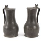 Two pewter measures of baluster form with acorn finials, each 28cm high,