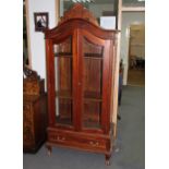 An arch top display cabinet with glazed doors and sides, fitted adjustable shelves,