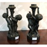 A pair of bronzed metal figural candlesticks, with putti supports,