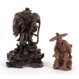 An Oriental root wood carving of a luohan carrying a lion raised on a pierced floral hardwood stand,