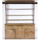 A pine dresser with shelves over, fitted drawers and cupboards beneath,