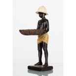 A resin figure of a standing boy wearing pith helmet and holding a basket,