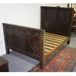 A carved oak bedstead, the head board set floral panels and arches,