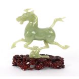 A jade carving of a galloping horse, on a stand,