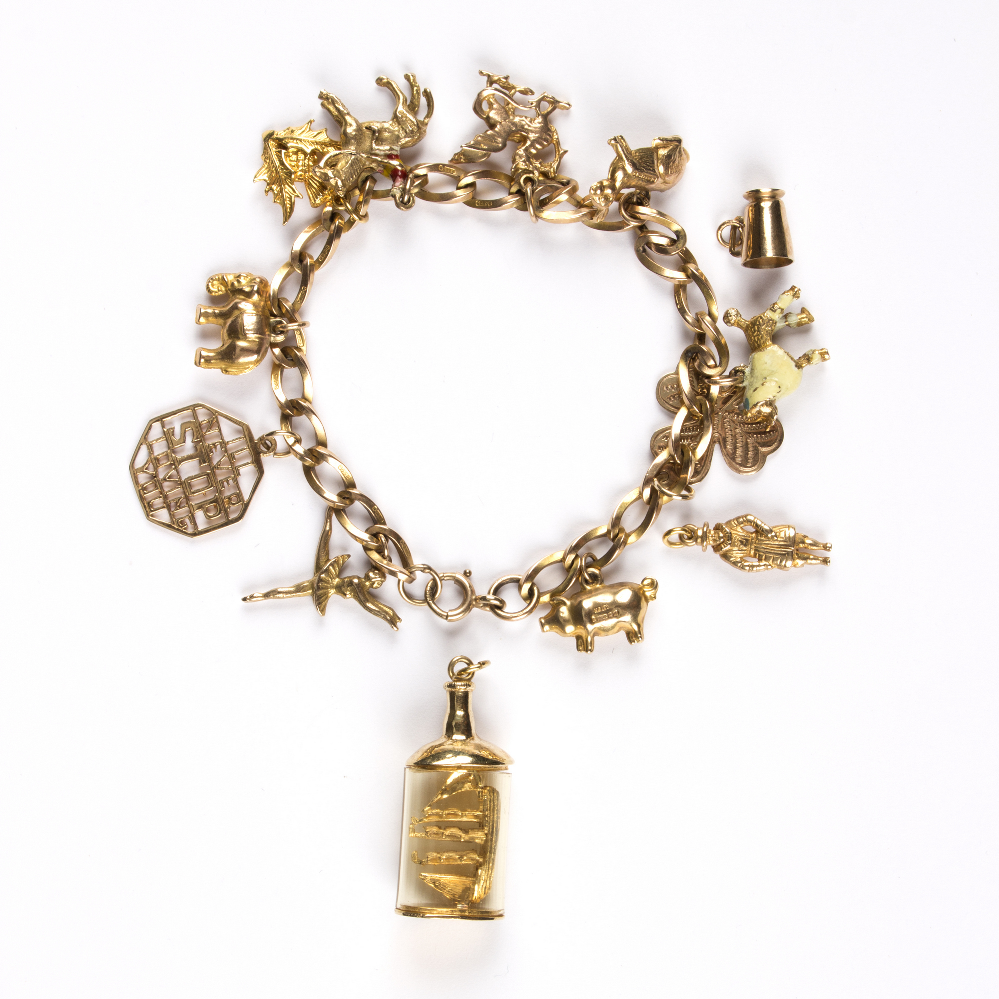 A gold charm bracelet, charms to include a ship in a bottle, a ballerina, Welsh dragon etc.