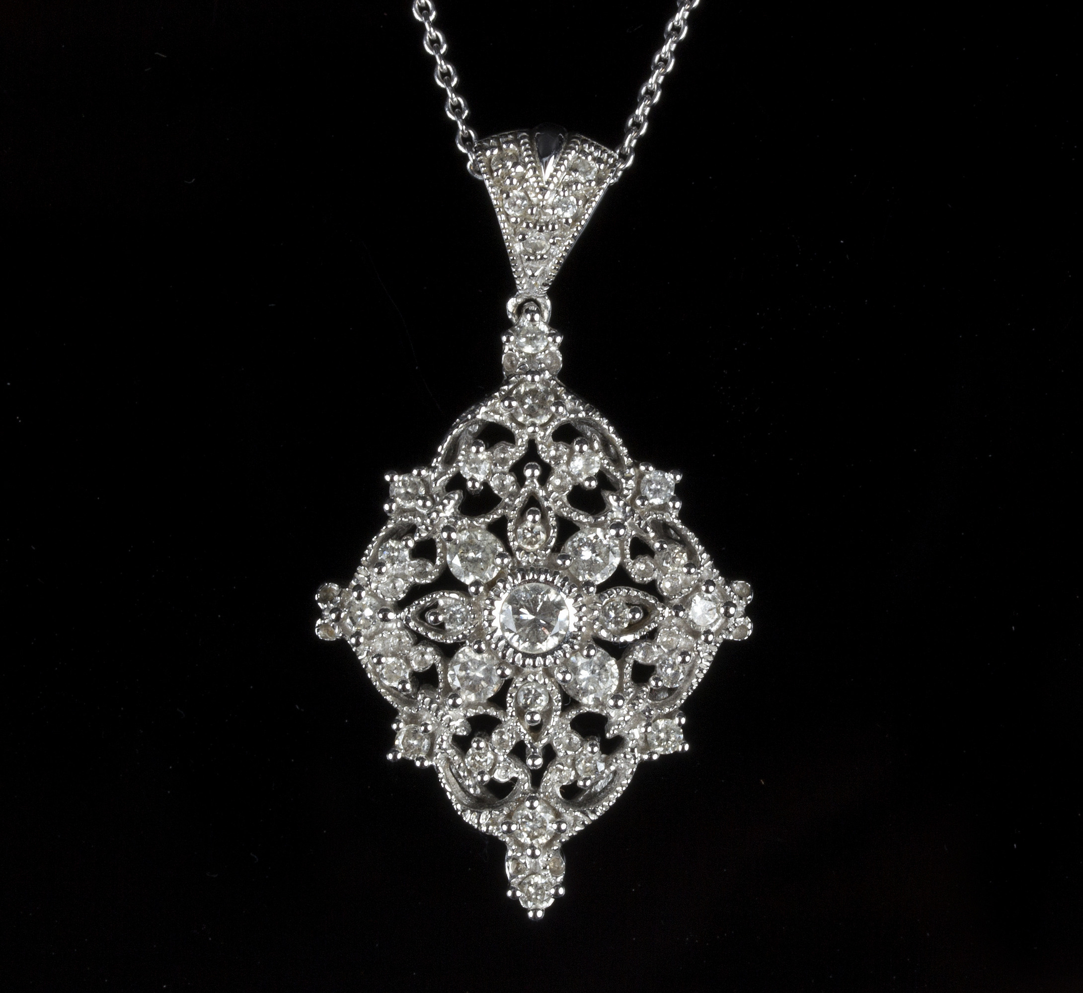 A diamond pendant of pierced foliate design to a 14k white gold mount, the central stone 0.