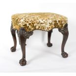 An upholstered stool on carved cabriole legs and ball and claw feet,