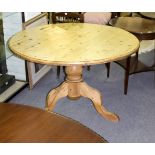 A pine table, the circular top on a tripod base,