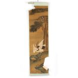 A Chinese scroll painting depicting a red-crowned crane amongst rocks and peonies with pine trees