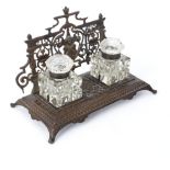 A bronze desk inkstand, fitted two glass inkwells with hinged covers and pen support,