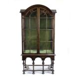 A walnut arch top cabinet of late 17th Century design on a stand with four turned legs,