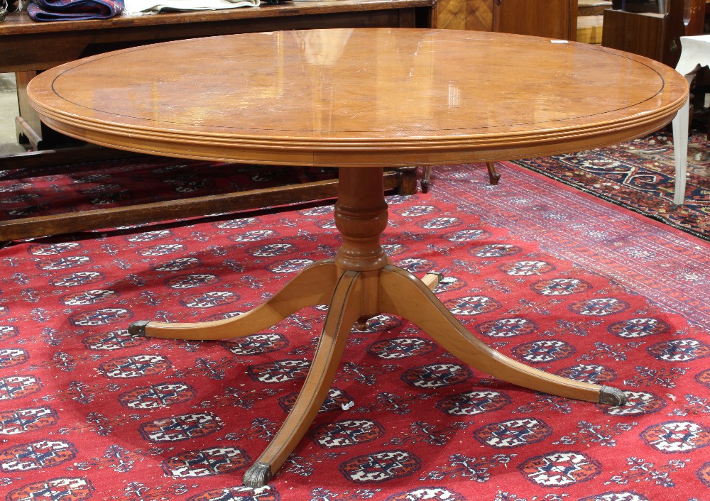 Regency style dining table, the circular top having ebonized banding, and rising on a pedestal