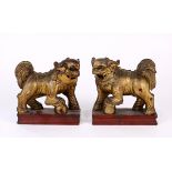 (lot of 2) Chinese gilt wood fu-lions, each with a foreleg resting on a ball, all raised on a red