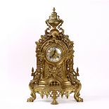 Rococo Revival style brass mantle clock, the round face with enamel Roman numerals, rising on a