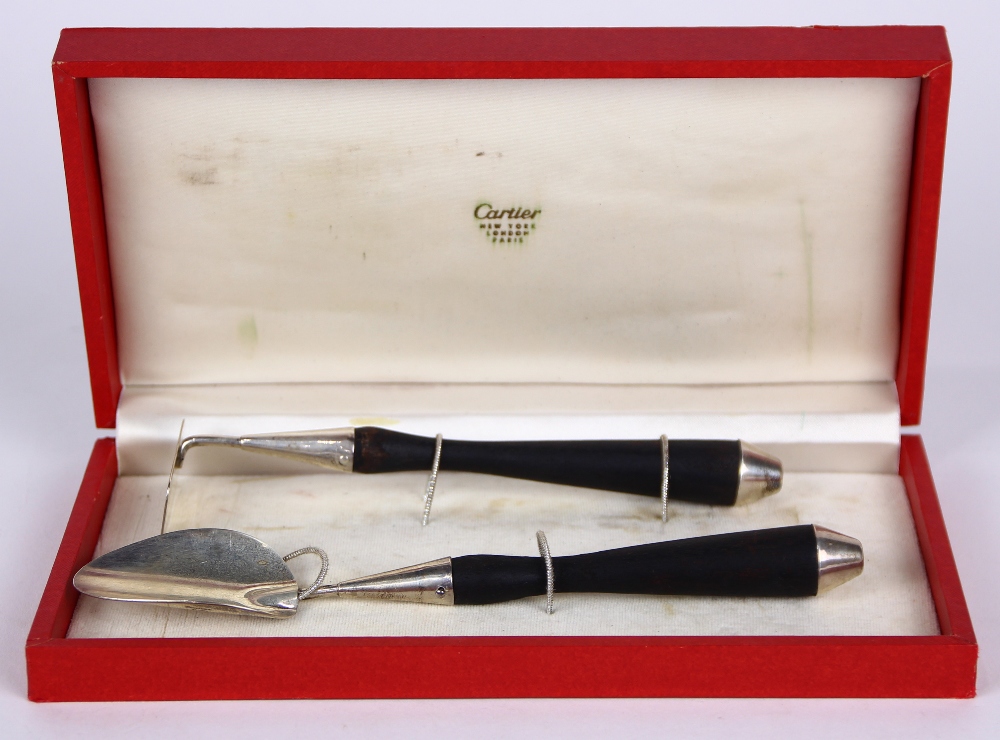 (lot of 2) Cartier silver utensil group, consisting of a sterling and wood handle pusher, 7"l;
