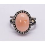 Coral, diamond, 18k gold and blackened silver ring Centering (1) oval-cut coral, measuring