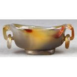 Chinese agate libation cup, the scroll handles suspending loose rings, raised on a low support, 3.