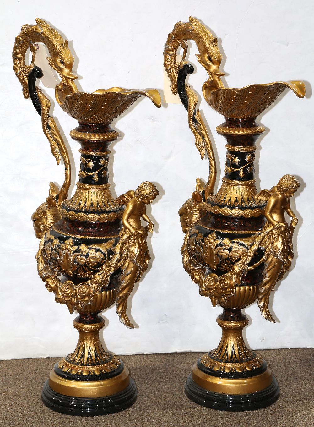 Pair of monumental Neoclassical style ewers, each having a dolphin form handle, above the