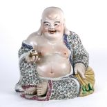 Chinese enameled porcelain Budai, seated in royal ease in a loose robe, holding an ingot in his