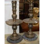 Pair of Indian brass candle prickets, having a turned standard with a wide flaring wax pan and