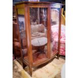 Edwardian bow front vitrine, 20th Century, having two inset glass panels and rising on square