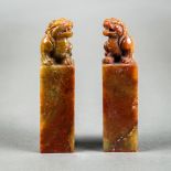 (lot of 2) Chinese soapstone seals, each of a qilin seated on its haunches, above a tall plinth,