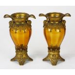 Continental amber glass urns, each having a Classical form with gilt metal handled sides accented