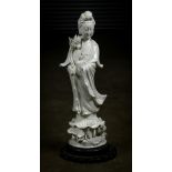 Chinese blanc de chine porcelain Guanyin, holding a lotus, standing above an elaborate lotus