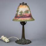 Reverse painted table lamp, having a domed shade decorated with a scenic reserve and rising on a