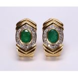 Pair of emerald, diamond and 14k yellow gold earrings Featuring (2) oval-cut emeralds, weighing a