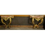 (lot of 2) Italian Rococo style giltwood console tables, each having a shaped marble top, above a