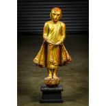 Southeast Asian gilt lacquered Buddhist figure, featuring a monk in monastic robes, standing on a