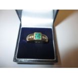 An 18ct gold ring set with large square Emerald flanked by diamonds to the shoulders