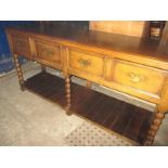 An oak four drawer buffet with under tier supported on barley twist columns