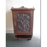 An oak wall mounted cupboard with carved wood door