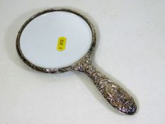 A silver mirror with embossed decor